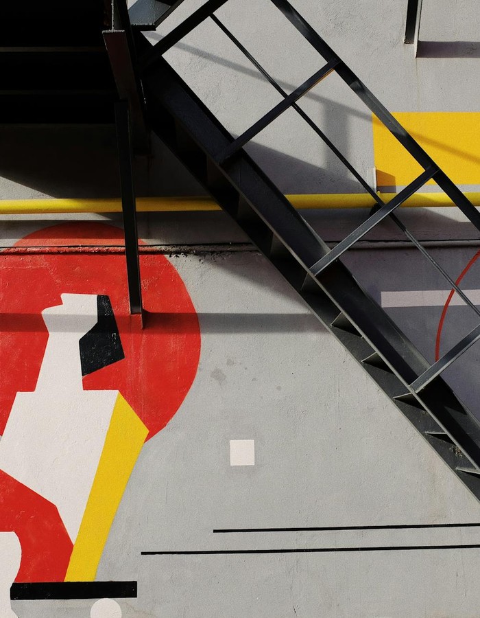 Black metal staircase installed near gray wall with colorful graffiti on facade of modern building on street in city